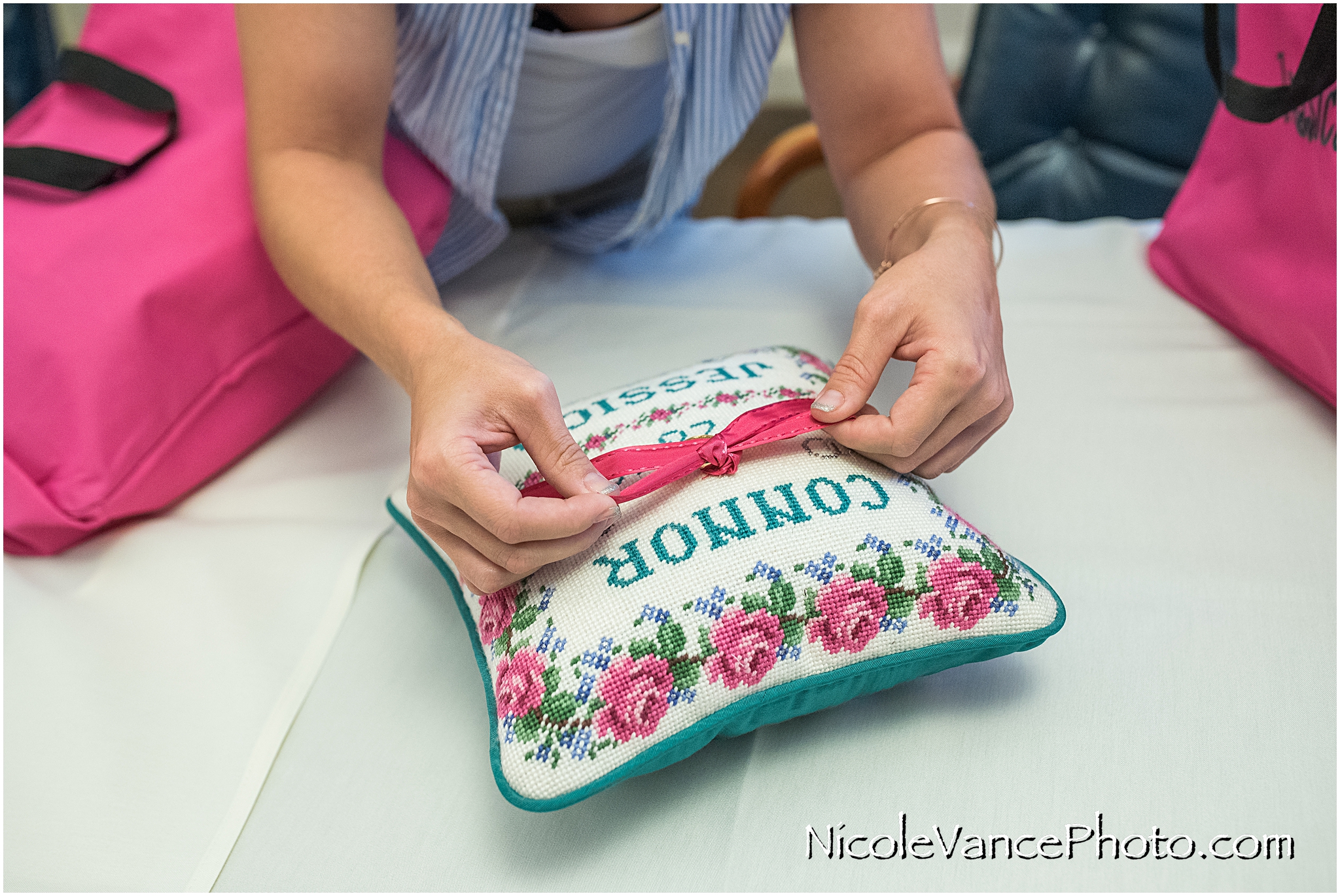 A bridesmaid ties the rings on the ring pillow before the ceremony at Virginia Crossings.