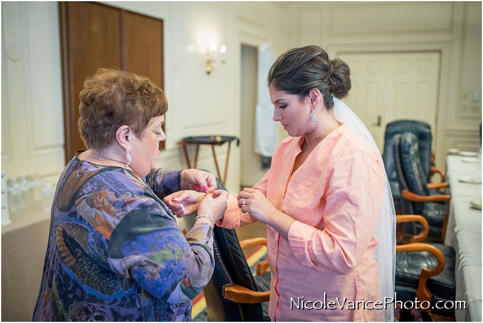 Mom helps the bride put on her bracelet in the conference room at Virginia Crossings.