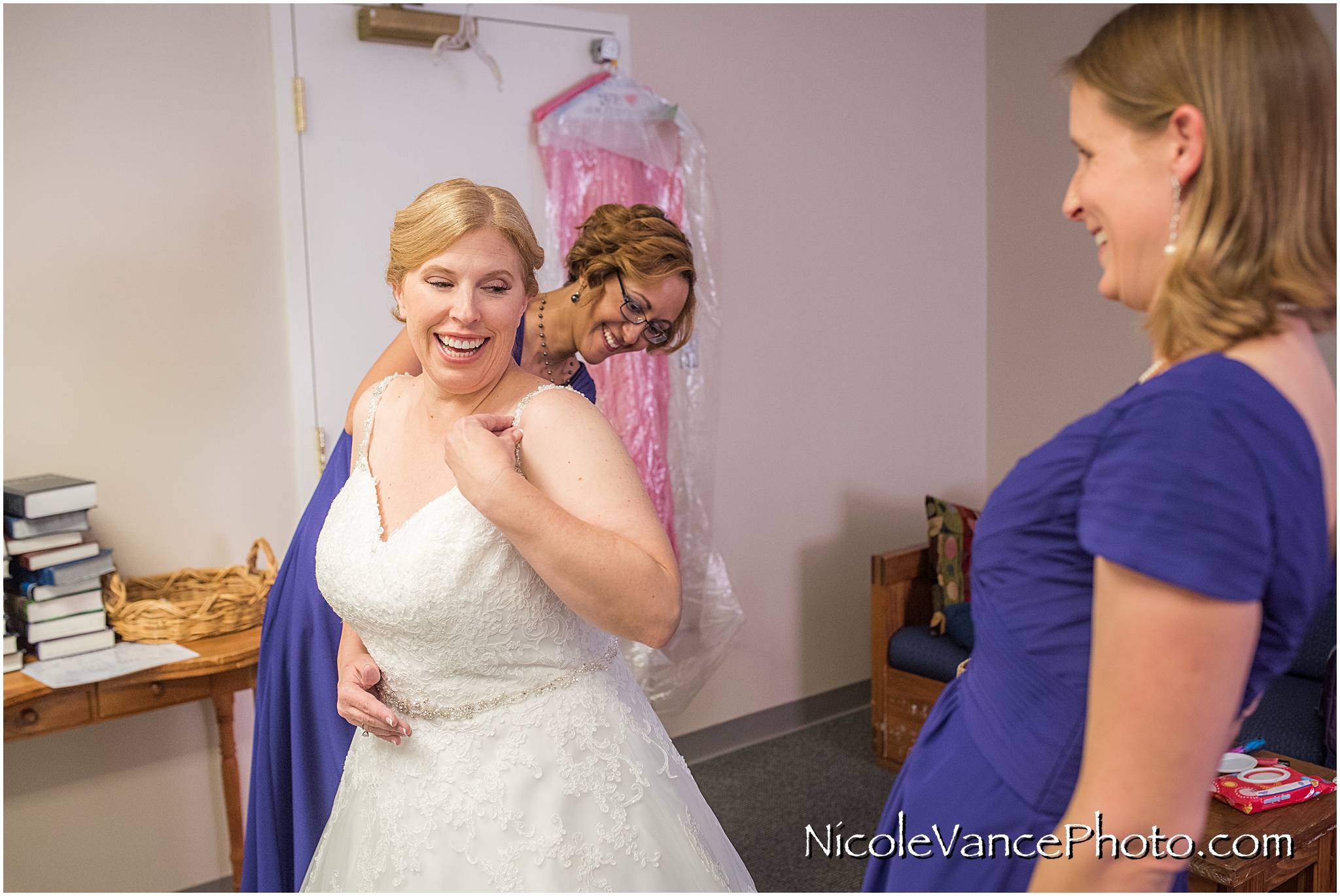 Bridemaids help the bride put on her bridal gown, a Jessica Ingram design.