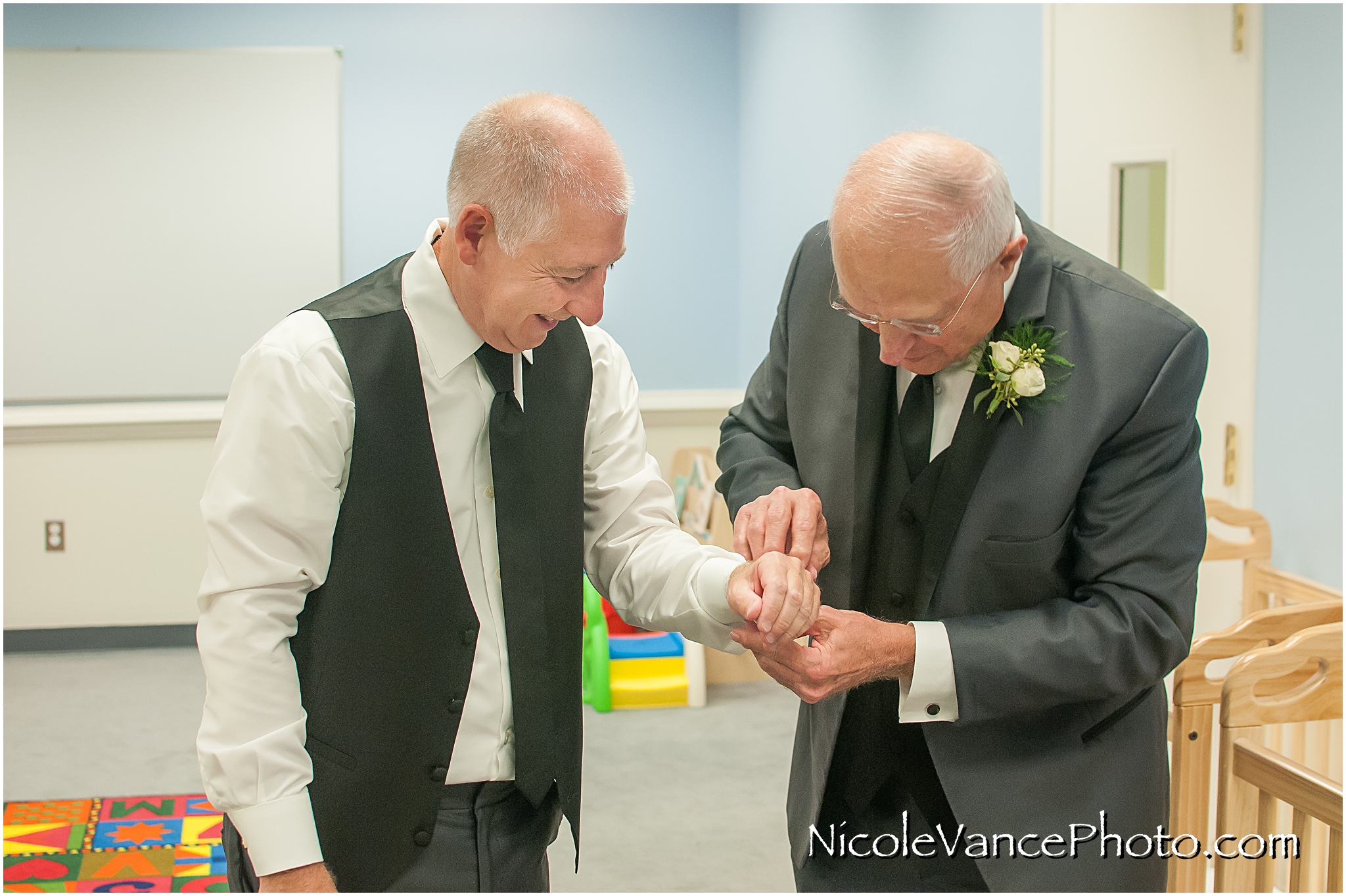 The bride's dad helps the groom with his cufflinks.