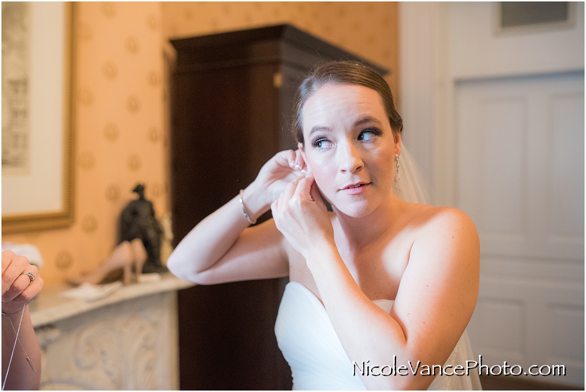 The bride puts on her earrings in her room at the Linden Row Inn.