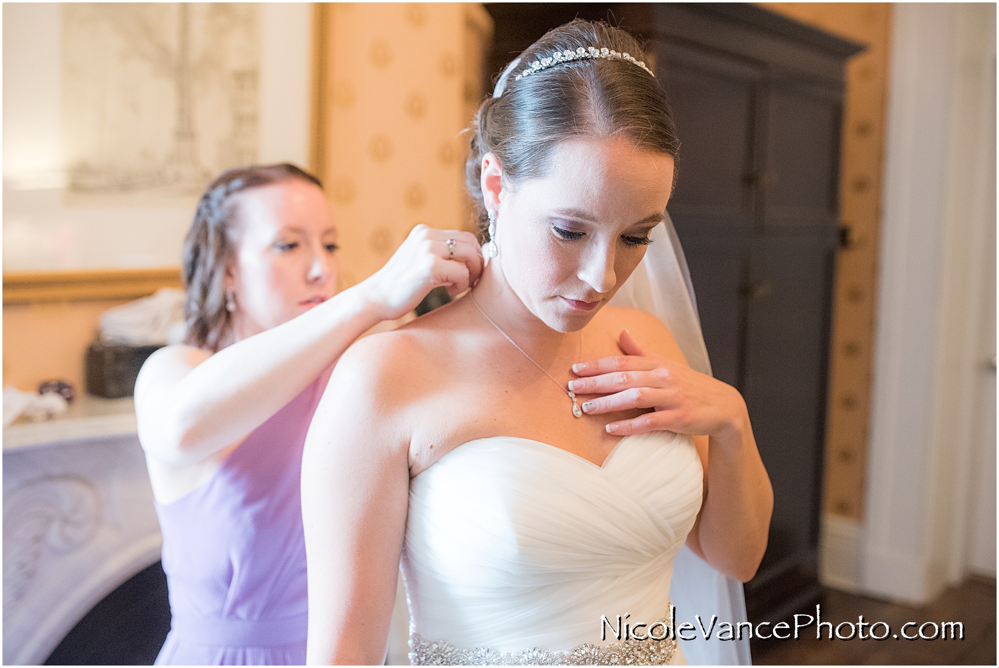 The bride gets help with her necklace.