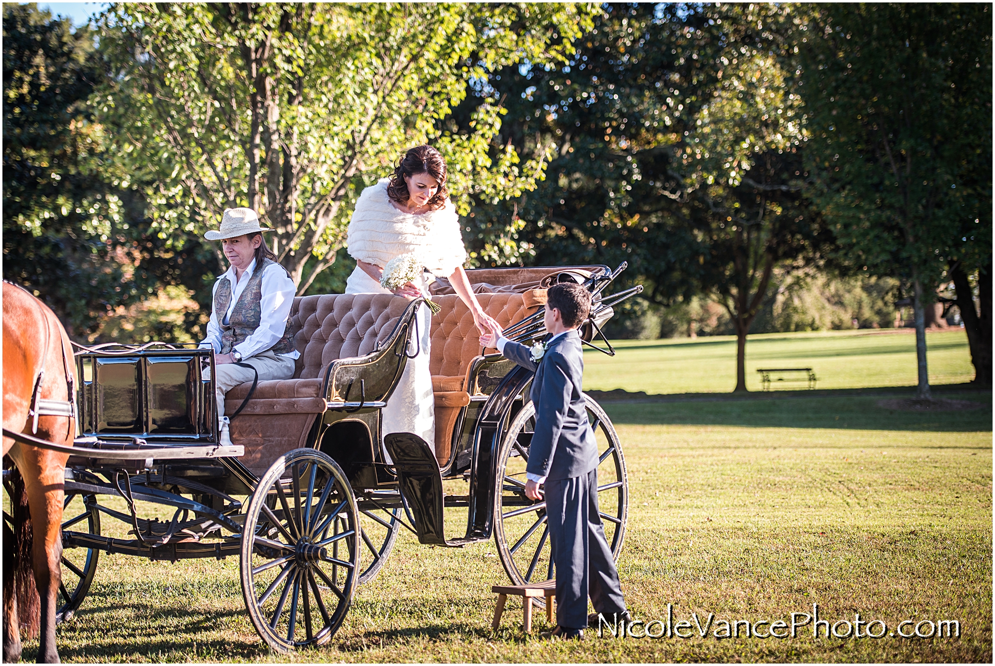 The bride arrives via horse drawn carriage at her wedding ceremony at Maymont Park in Richmond Virginia.