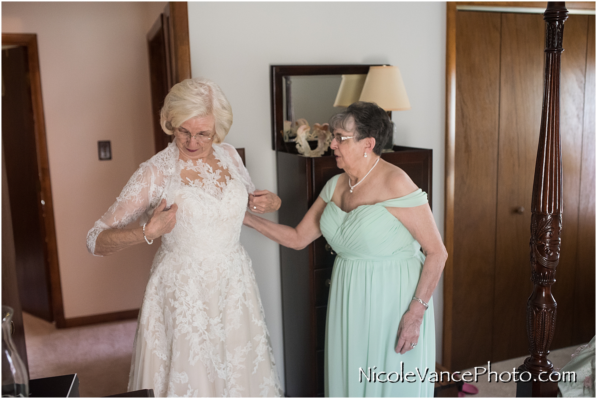 The bride's sister helps her put on her wedding bolero as she prepares for her wedding.