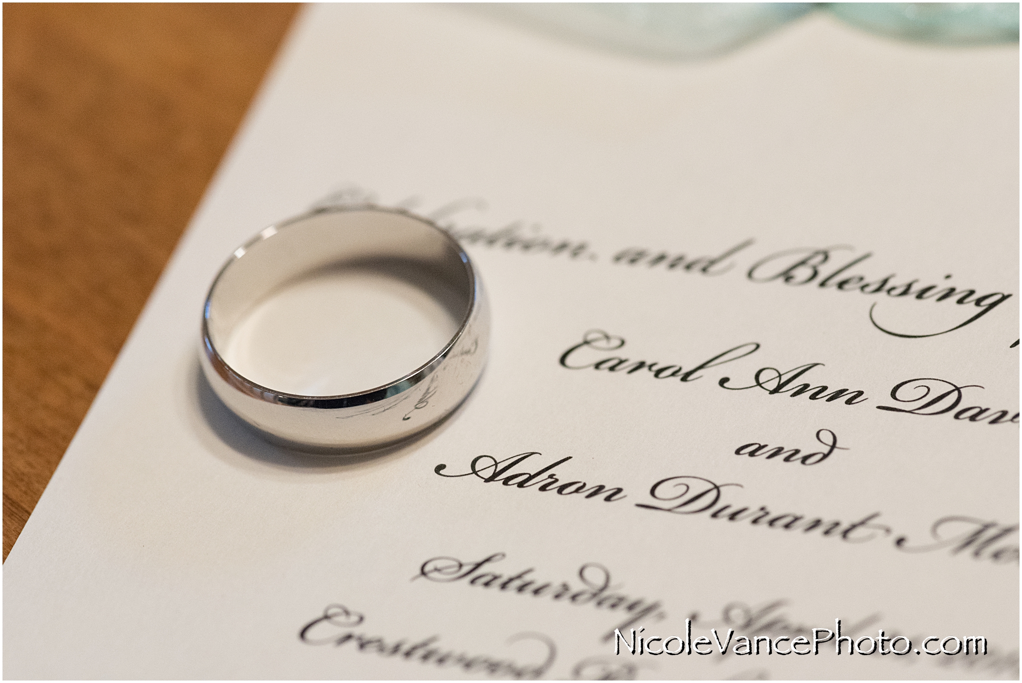 The groom's ring sits on the wedding invitation.